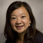 A smiling Asian woman wearing a brown shirt. 